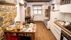 A cozy kitchen with stone walls, wooden beams, a dining area with a table set for two, and a built-in oven. - The Key Of Bergamo.Fronte Mura is an elegant apartment located on Via Pignolo (Bergamo)
