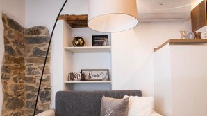 A cozy living room with a grey sofa, a white lamp, and a stone wall. - The Key Of Bergamo.Fronte Mura is an elegant apartment located on Via Pignolo (Bergamo)