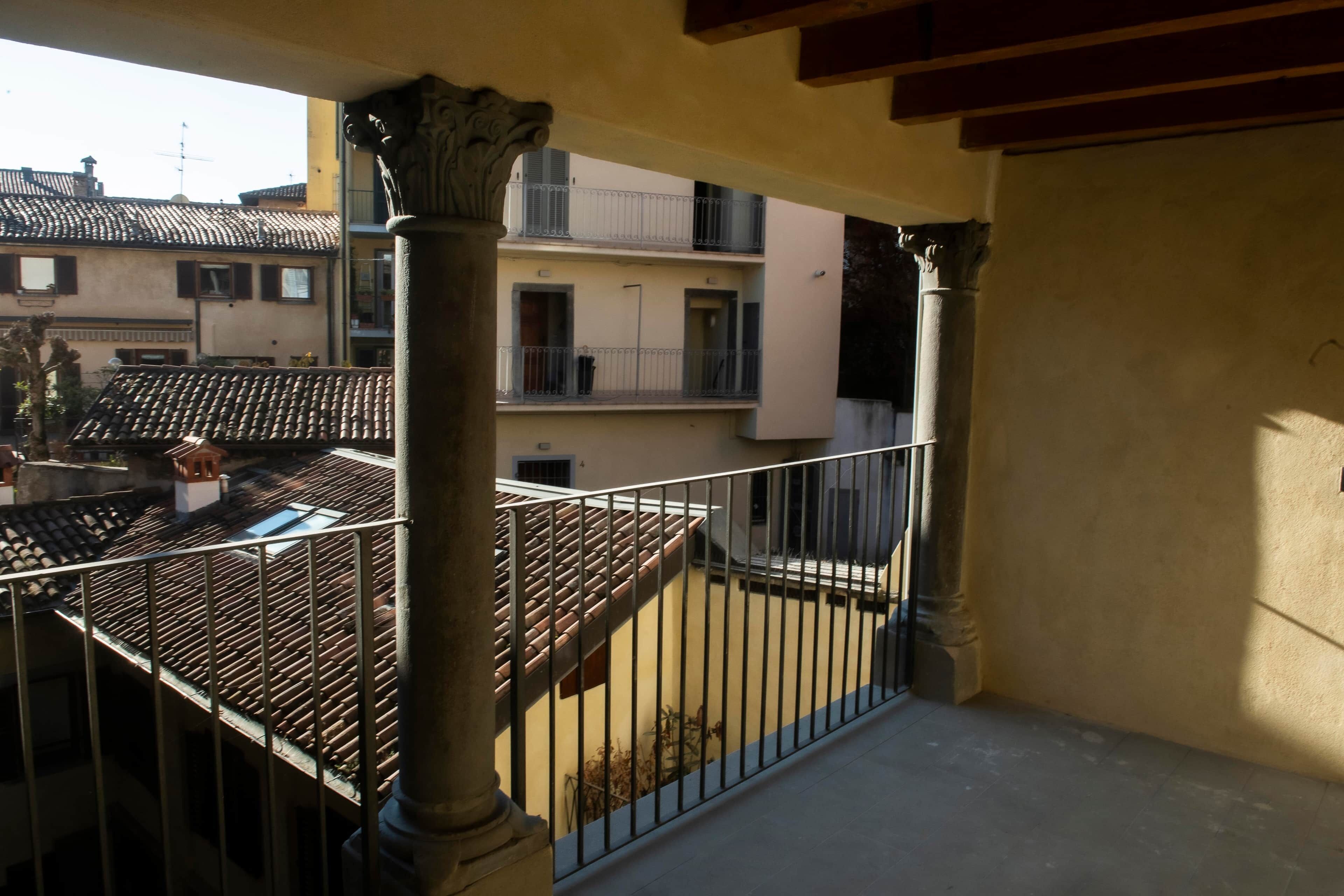 A balcony with a tiled roof, a metal railing, and a view of adjacent buildings.