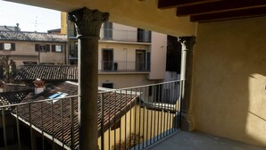 A balcony with a tiled roof, a metal railing, and a view of adjacent buildings. - The Key Of Bergamo.Fronte Mura is an elegant apartment located on Via Pignolo (Bergamo)