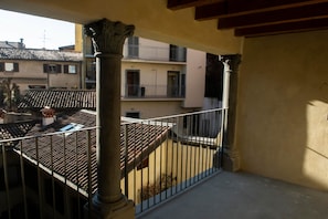 Ein Balkon mit Ziegeldach, Metallgeländer und Blick auf angrenzende Gebäude.