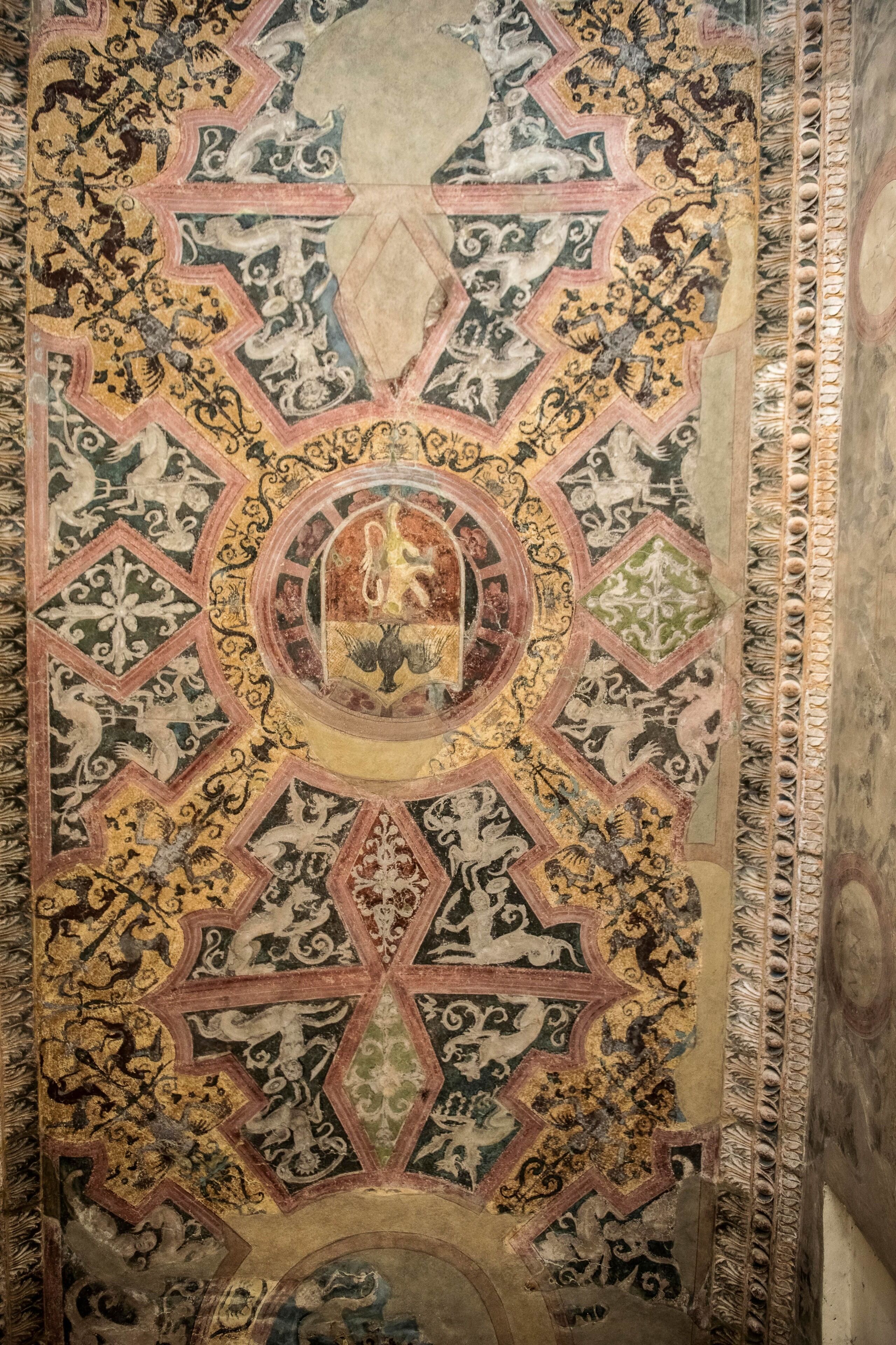 A detailed ceiling with intricate geometric patterns and a central circular design.