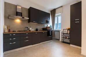 Une cuisine moderne avec des meubles de couleur sombre, une cuisinière à gaz, un four à micro-ondes et un four encastré.