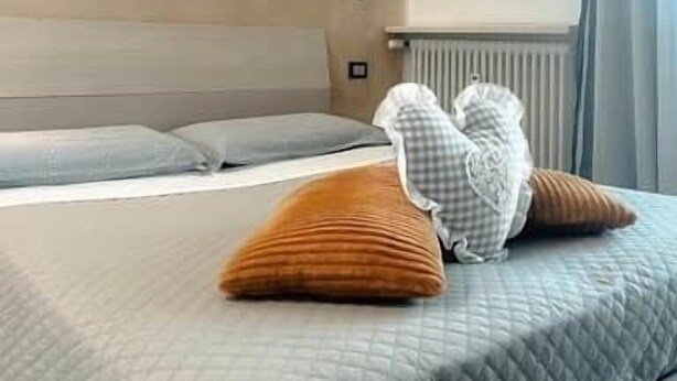 Een moderne hotelkamer met een groot bed, een hoofdbord en een raam met gordijnen.