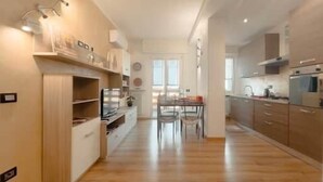 Een moderne keuken met houten kastjes, een eethoek met stoelen en een ingebouwde oven.
