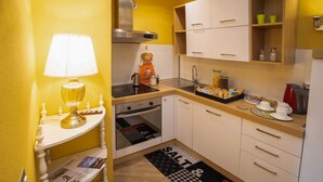 Eine kleine Küche mit Herd, Backofen, Spüle und einer Arbeitsfläche mit Wasserkocher und Gläsern.