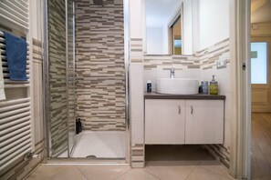 A modern bathroom with a glass shower enclosure, a white sink, and a mirror above it. - Colleoni 20. Standard Apartment. Apartment located in the Upper Town, at Via Colleoni 20. (Bergamo)