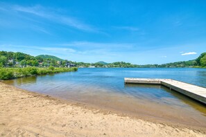 A river with a sandy beach and a wooden dock extending into the water. - Grace Haven (Lake Junaluska)