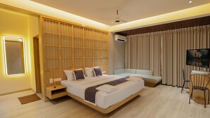 A modern hotel room with a large bed, a seating area, a desk, and a large window with curtains. - Mihra Mist (Mananthavady)
