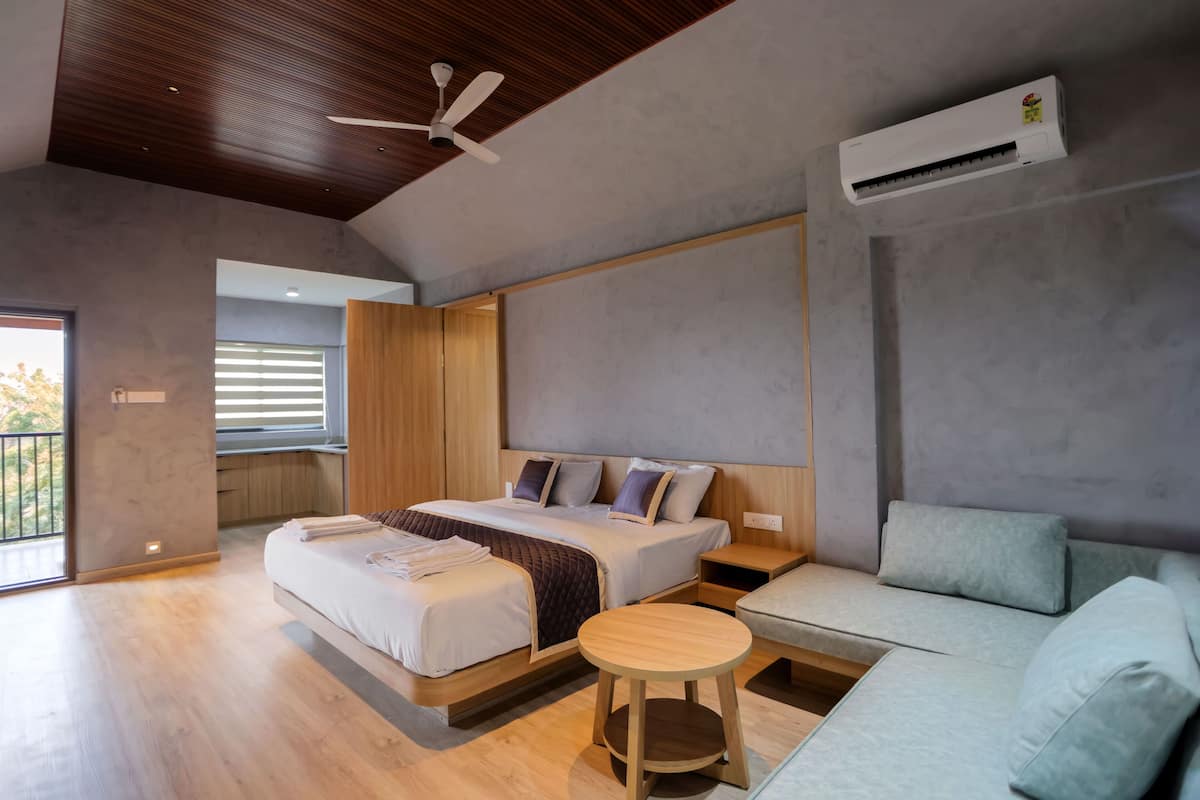 Una habitación de hotel moderna con una cama grande, un sofá, una pequeña mesa redonda y un equipo de aire acondicionado.