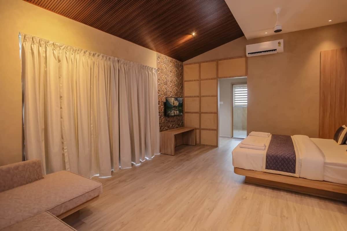 Un dormitorio moderno con techo de madera, una cama, un sofá y una pared de piedra.