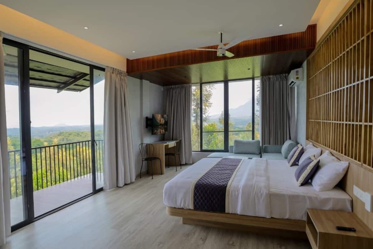 Un dormitorio con una cama grande, un escritorio y vistas al exterior.