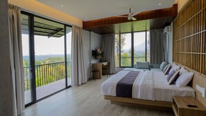 A bedroom with a large bed, a desk, and a view of the outdoors. - Mihra Mist (Mananthavady)