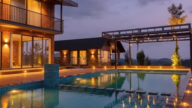 A modern two-story building with a swimming pool, outdoor lighting, and a covered area with a view of the landscape. - Mihra Mist (Mananthavady)