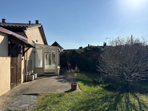 A house with a conservatory, a stone pathway, and a garden.
