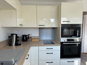 A modern kitchen with white cabinets, a built-in oven, and a coffee maker.