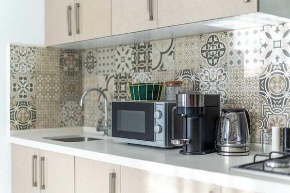 A kitchen with a microwave, coffee maker, and kettle on the counter.