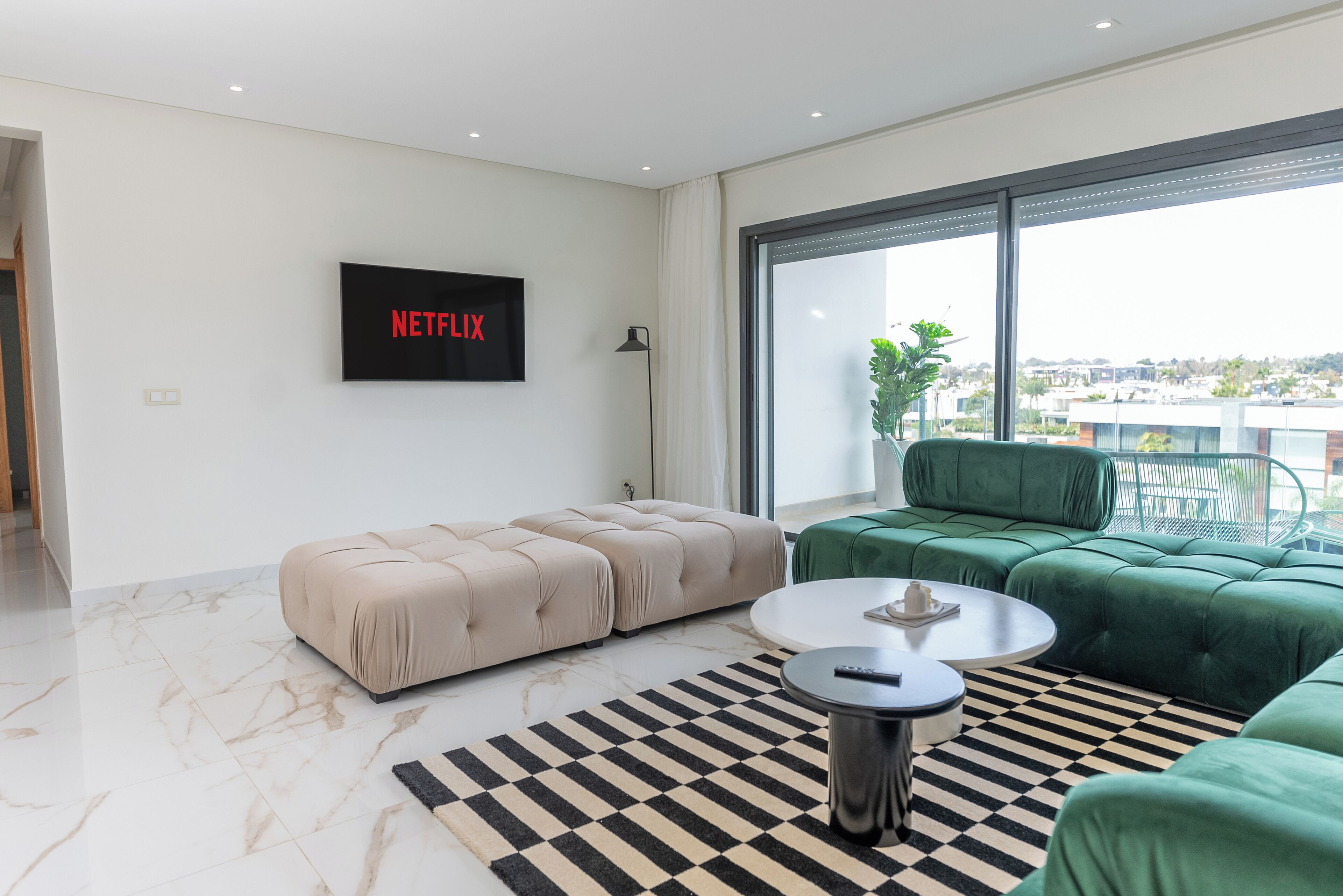 A modern living room with a sofa, ottoman, coffee table, and a TV mounted on the wall.
