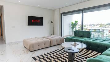A modern living room with a sofa, ottoman, coffee table, and a TV mounted on the wall.