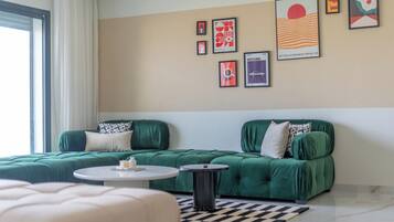 Una sala de estar moderna con un sofá verde, una mesa de centro redonda y una alfombra a cuadros.