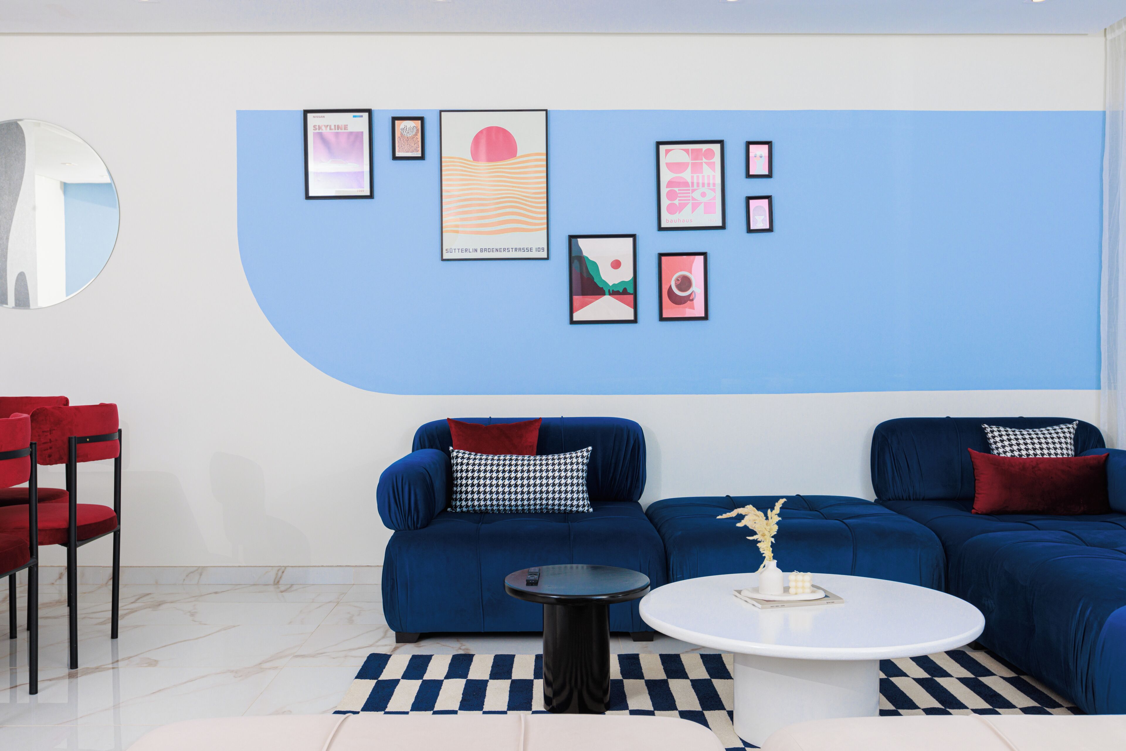 Una sala de estar moderna con un sofá azul, una mesa de centro redonda y una silla roja.