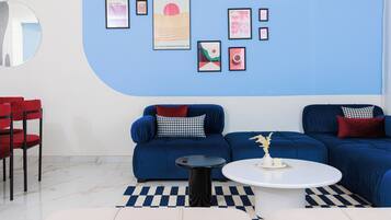 Una sala de estar moderna con un sofá azul, una mesa de centro redonda y una silla roja.
