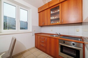 Una cuina amb armaris de fusta, un vàter d'acer inoxidable i un forn encastrat.