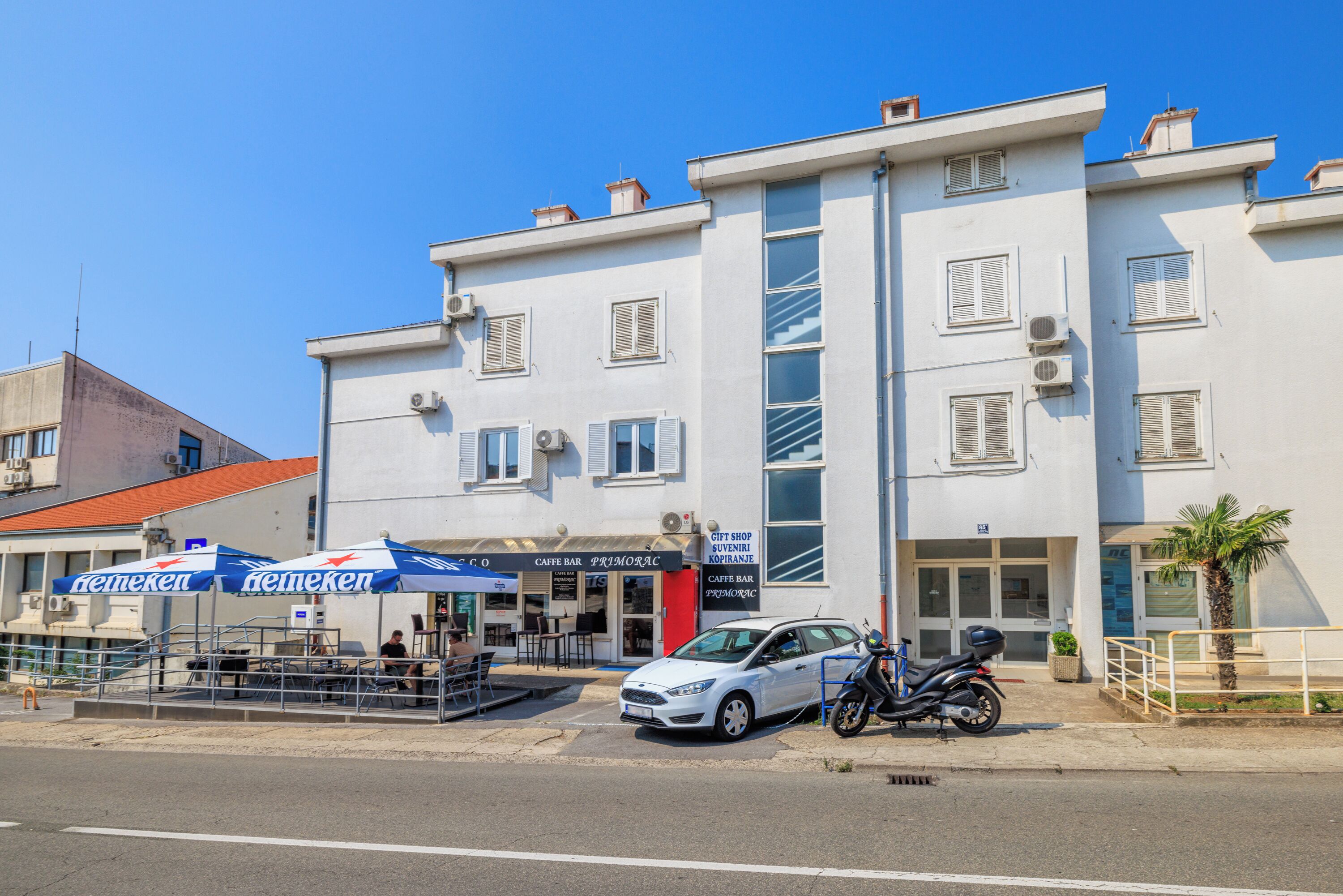 A building with a cafe bar, a gift shop, and a car parked in front.