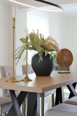 A modern dining table with a vase of greenery, two candle holders, and a decorative plate. - Villa Isabella - Rooftop Jacuzzi (Chania)