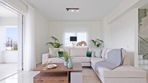 Ein modernes Wohnzimmer mit einer Couch, einem Couchtisch und Topfpflanzen.
