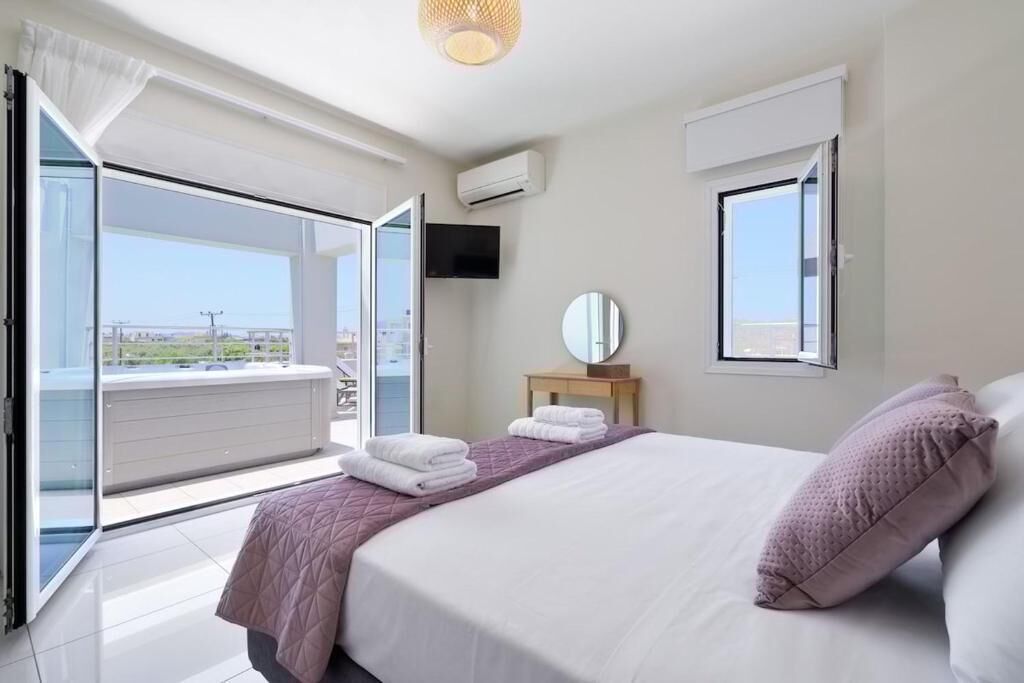 A bedroom with a bed, a TV, a window, and a balcony.