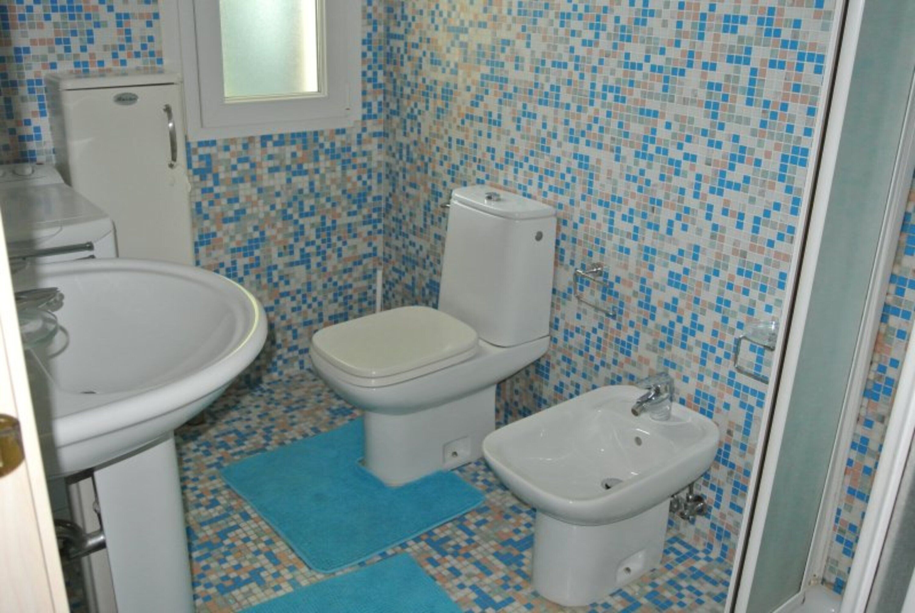 A bathroom with a toilet, bidet, and sink.