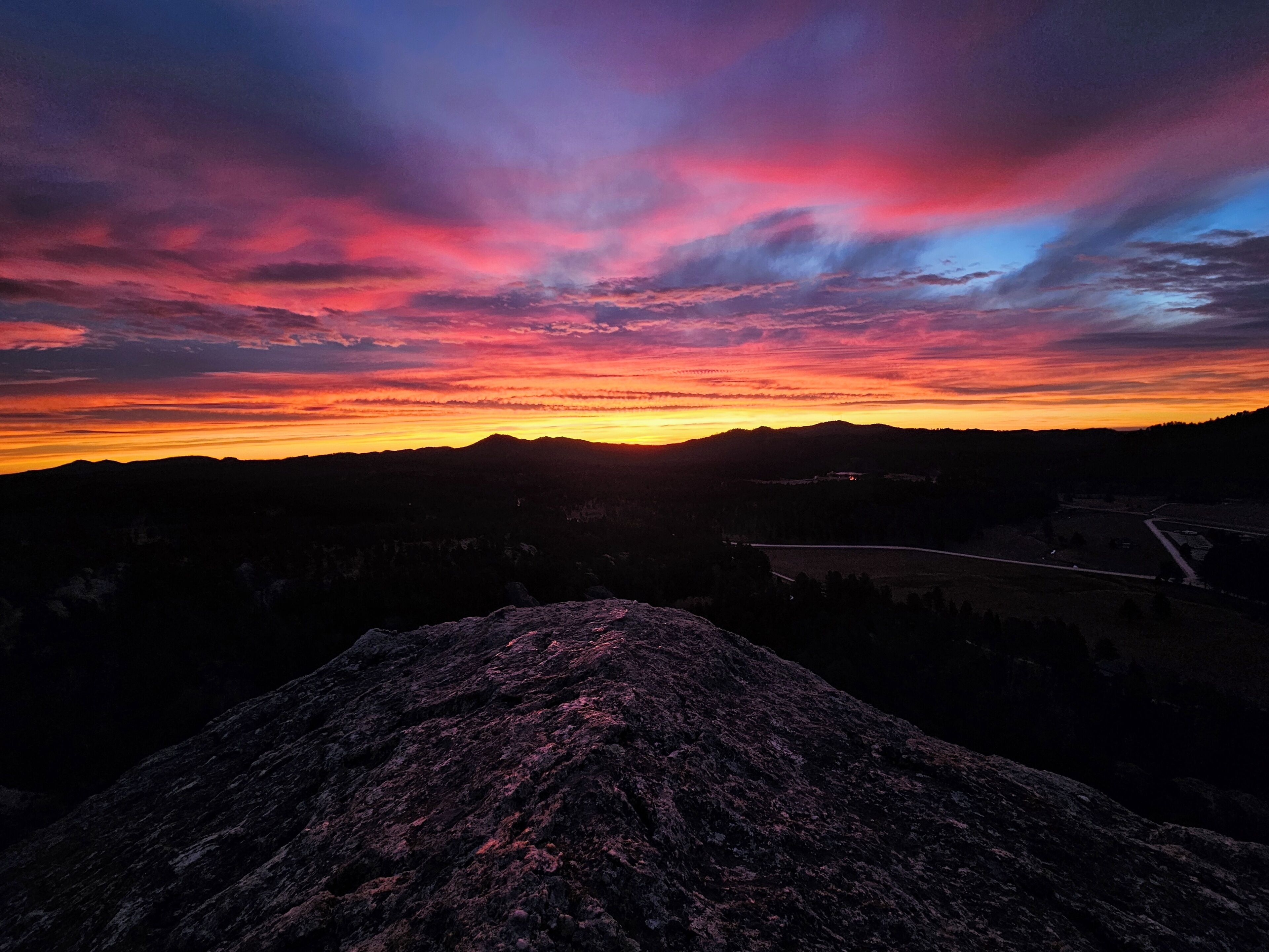 Un paysage montagneux au coucher du soleil, avec un ciel dégagé.