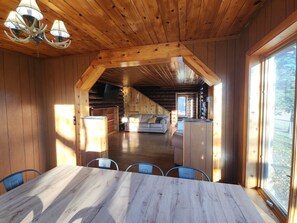 Un interior de madera con una mesa de comedor, sillas, un sofá y una araña.