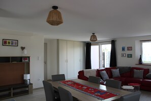 Un salon moderne comprenant un coin repas, un canapĂ© rouge et une grande fenĂȘtre avec des rideaux.