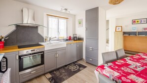 A modern kitchen with grey cabinets, a stainless steel oven, a sink, and a window with curtains.