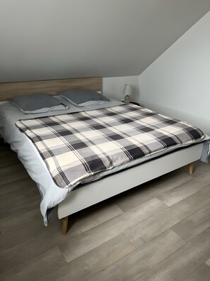 Ein Schlafzimmer mit einem Bett, Kissen, einer Nachttischlampe und Holzboden.