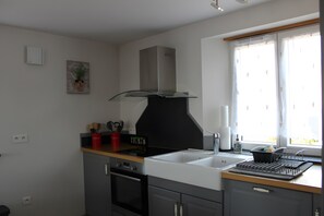 Eine moderne Küche mit Herd, Backofen, Spüle und einem Fenster mit Vorhängen.