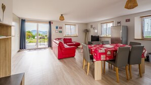 A spacious living area with a red sofa, a dining table with chairs, and a kitchen area.