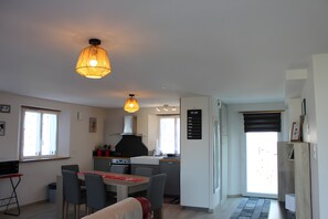 Une cuisine compacte avec un coin repas, une liste de tĂąches Ă faire accrochĂ©e au mur et une vue sur lâextĂ©rieur.