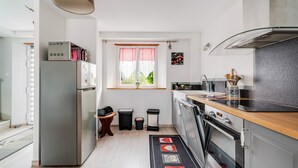 Een kleine keuken met een koelkast, oven en spoelbak.