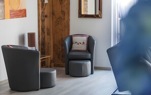 Un salon moderne avec un canapĂ© gris foncĂ©, un mur dâaccent en bois, un miroir encadrĂ© et une petite table avec une lampe.