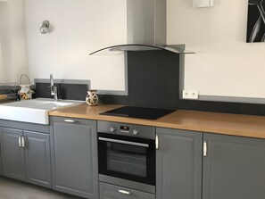 Une cuisine moderne équipée d’un évier, d’une cuisinière, d’un four et d’une hotte noire.