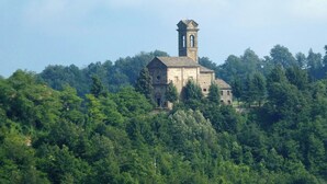 A historic stone building with a bell tower, surrounded by dense forest. - Charming Historic House in Provincia di Cuneo, Italia (Mombarcaro)