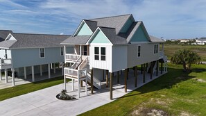 Ein Haus am Wasser mit zwei Etagen, inklusive Balkon, überdachter Veranda und einer Treppe zum oberen Stockwerk.