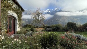 Una casa con jardín, una montaña al fondo y cielo despejado.