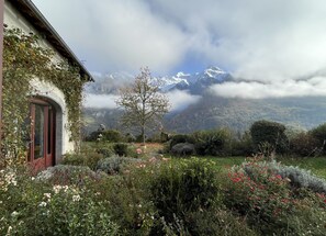 Ein Haus mit Garten, im Hintergrund ein Berg und ein klarer Himmel.