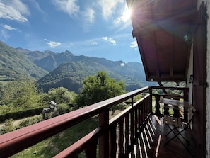 A wooden deck with a view of mountains and greenery.