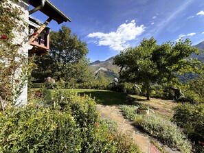 Un jardin avec un sentier en pierre, des arbres et une chaĂźne de montagnes en arriĂšre-plan.