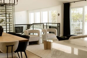 A modern living room with a sofa, two armchairs, a coffee table, and a dining area with a table and chairs. - Elite Lakehouse w/ Hot Tub & Sauna (Mount Uniacke)